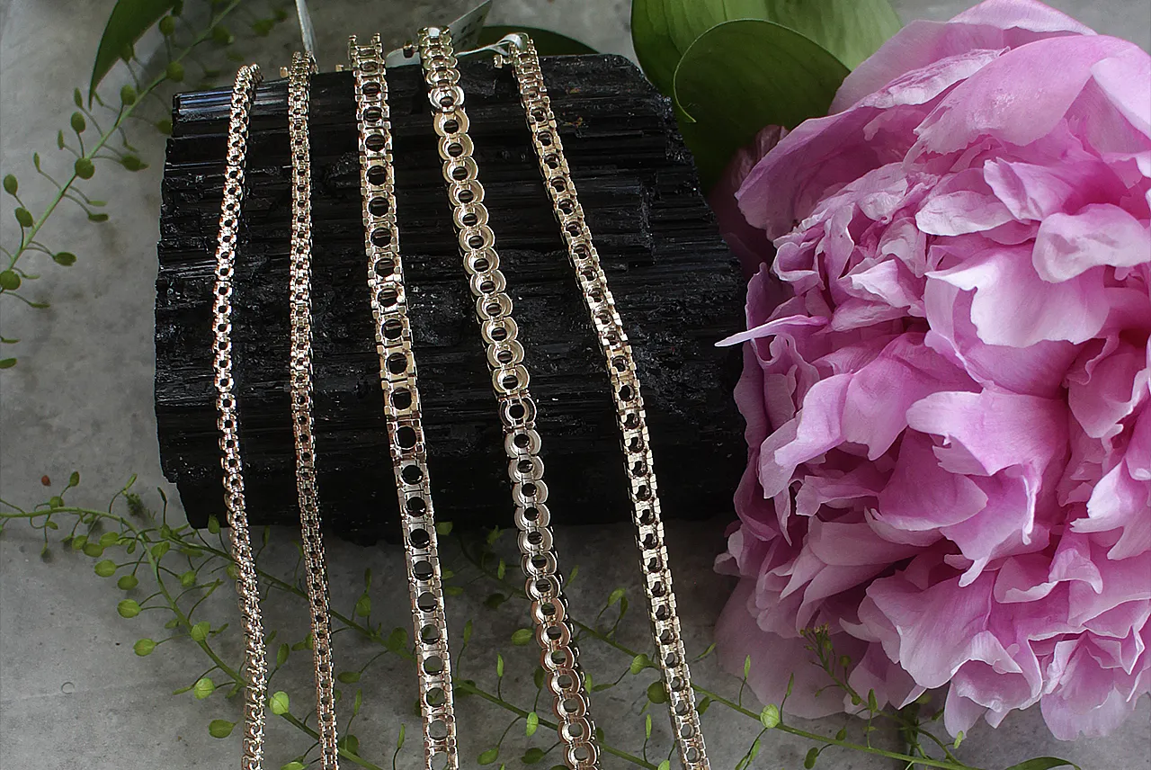 Several gold chains in different weights laid across slate, each priced per gram
