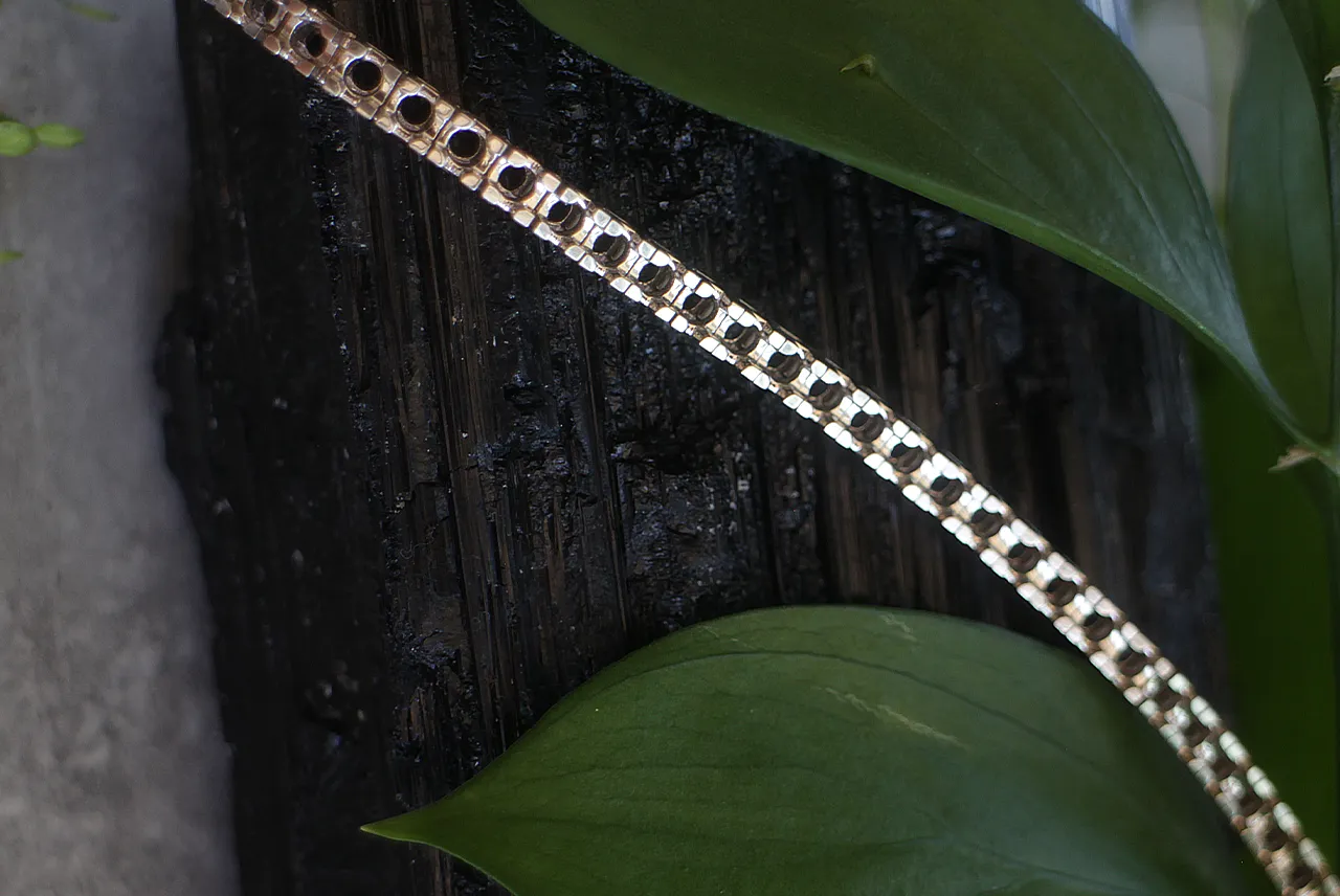Gold chain on a dark wood bench, the kind of repair job costed by weight